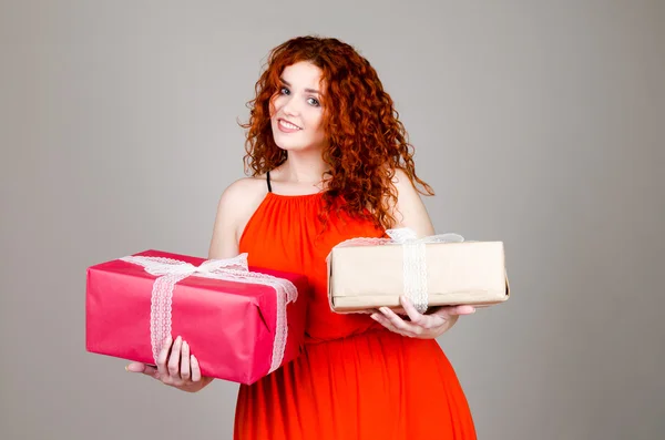Mooi dik meisje met rood haar met een doos van de gift in de hand op een grijze achtergrond — Stockfoto
