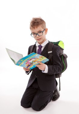 Beyaz arka plan üzerinde izole bir kitap yere sırt çantası ile şirin küçük çocuk