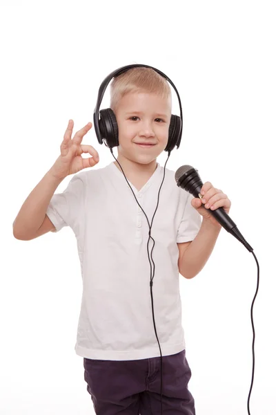 Niño en auriculares, cantando en un micrófono aislado sobre fondo blanco —  Fotos de Stock