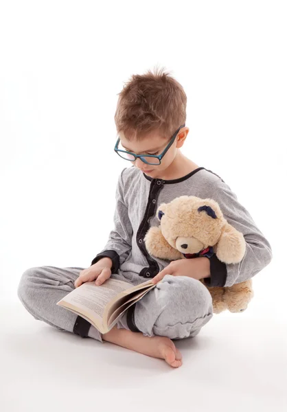 Niño en pijama con su osito de peluche y libro aislado sobre fondo blanco — Foto de Stock