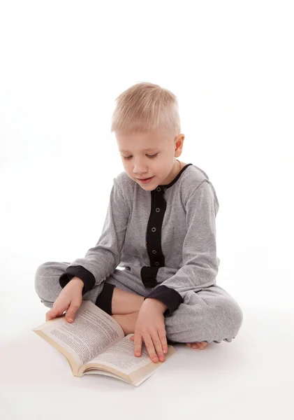 Lindo chico en pijama mirando imágenes en un libro de cuentos de hadas aislados sobre fondo blanco — Foto de Stock