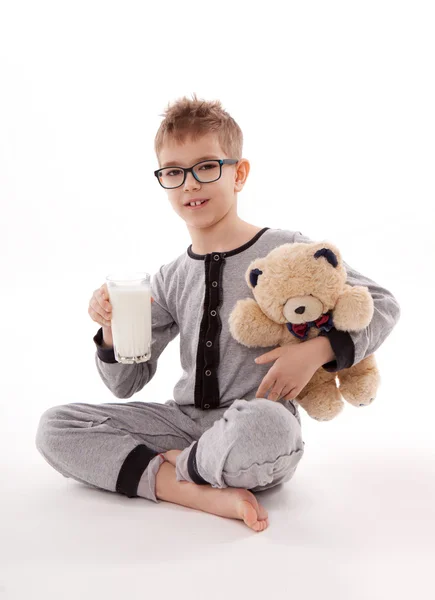 Boy v pyžamu, Medvídek a sklenici mléka izolovaných na bílém pozadí — Stock fotografie