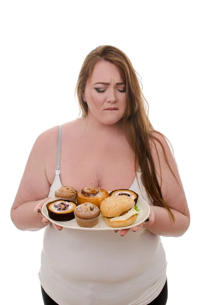 La mujer gorda con pasteles y hamburguesas en un plato en sus manos aisladas sobre fondo blanco — Foto de Stock