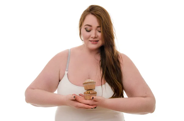 Şişman bir kadın ile bir muffin beyaz arka plan üzerinde izole onun elinde