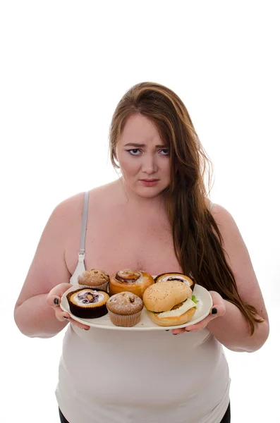 De dikke vrouw met cakes en hamburgers op een schotel in haar handen geïsoleerd op witte achtergrond — Stockfoto