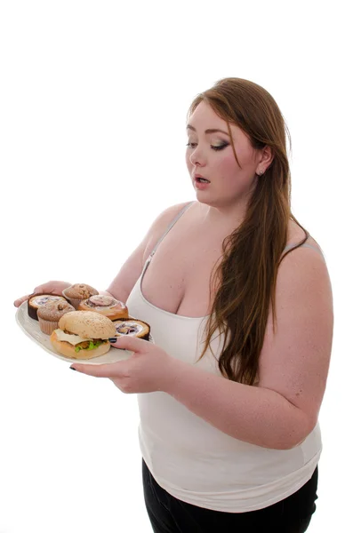 La mujer gorda con pasteles y hamburguesas en un plato en sus manos aisladas sobre fondo blanco — Foto de Stock