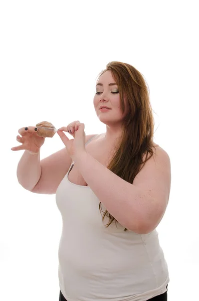 Tlustá žena s muffin v ruce izolovaných na bílém pozadí — Stock fotografie