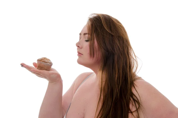 Şişman bir kadın ile bir muffin beyaz arka plan üzerinde izole onun elinde
