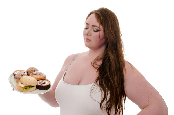 La donna grassa con torte e hamburger su un piatto in mano isolato su sfondo bianco — Foto Stock