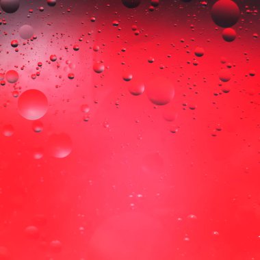 Kırmızı zemin üzerinde suya düşen bitkisel yağ damlaları.