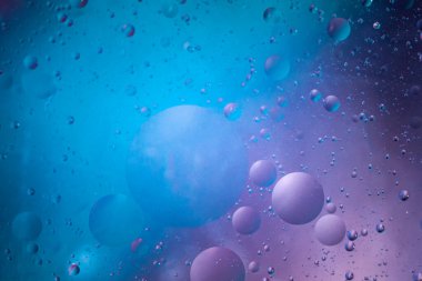 Çok renkli bir arka planda suya düşen bitkisel yağ damlaları. Damlalar uzaydaki gezegenlere benziyor..