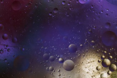 Çok renkli bir arka planda suya düşen bitkisel yağ damlaları. Damlalar uzaydaki gezegenlere benziyor..