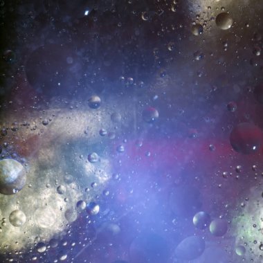 Mavi arka planda suya düşen bitkisel yağ damlaları. Damlalar gezegenleri ve yıldızları andırıyor..