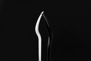 Siyah arka planda beyaz ve siyah plastik çatallar. Çatallar yan dururlar, dişlerle bağlanırlar..