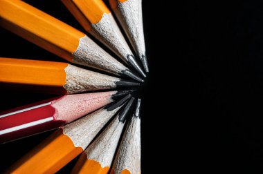 İş hayatında standart olmayan düşünce kavramı. Siyah arka planda yarım daire şeklinde dizilmiş sarı kalemler. Bir kırmızı kalem..