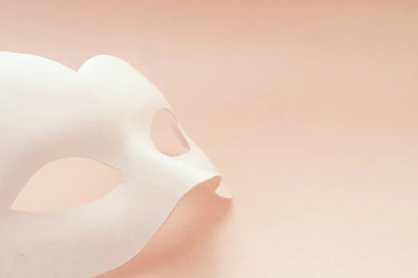 ピンクの背景に白いカーニバルマスク マスクは垂直に横たわっています — ストック写真