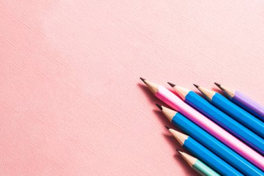Pastel pembe arka planda renkli kalemler..