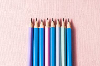 Pastel pembe arka planda renkli kalemler..