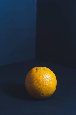 Odanın köşesinde koyu mavi bir tonda olgun bir portakal duruyor. Düzgün beslenme ve sağlıklı yaşam tarzı kavramı..