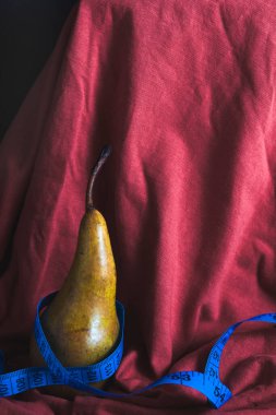 Kırmızı bir armut üzerine olgun bir armut mavi bir mezura ile sarılır. Düzgün beslenme ve sağlıklı yaşam tarzı kavramı..