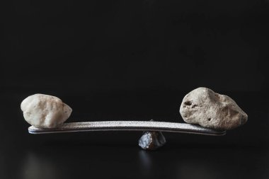 Dengeyi sağlamak için manivela üzerinde iki farklı boyutta taş var. Karanlık arka plan. Boşluğu kopyala.