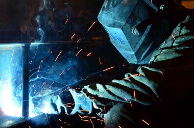 Fabrikada çalışan kaynakçılar metal üretiyorlar.