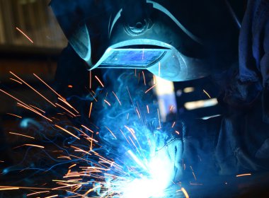 Fabrikada çalışan kaynakçılar metal üretiyorlar.