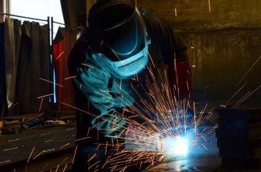 Fabrikada çalışan kaynakçılar metal üretiyorlar.
