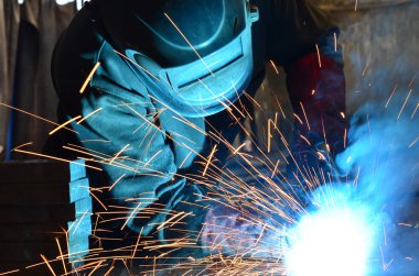 Fabrikada çalışan kaynakçılar metal üretiyorlar.
