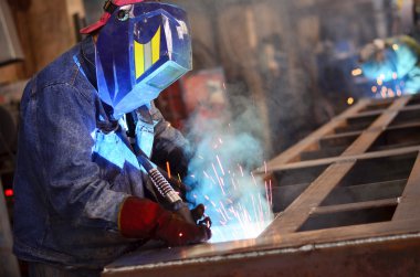Fabrikada çalışan kaynakçılar metal üretiyorlar.