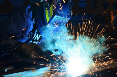 Fabrikada çalışan kaynakçılar metal üretiyorlar.