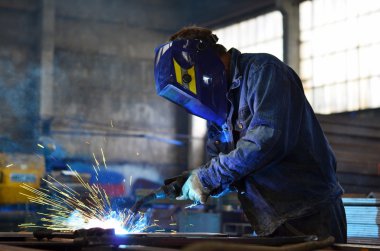 Fabrikada çalışan kaynakçılar metal üretiyorlar.