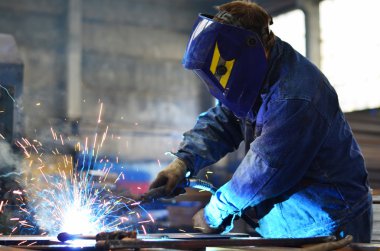 Fabrikada çalışan kaynakçılar metal üretiyorlar.