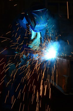 Fabrikada çalışan kaynakçılar metal üretiyorlar.
