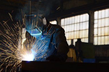 Fabrikada çalışan kaynakçılar metal üretiyorlar.