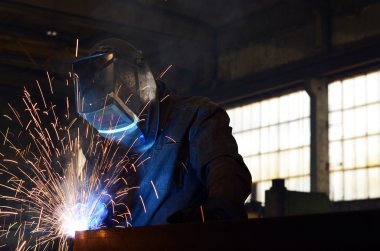 Fabrikada çalışan kaynakçılar metal üretiyorlar.