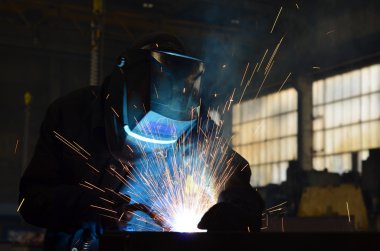 Fabrikada çalışan kaynakçılar metal üretiyorlar.
