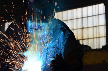 Fabrikada çalışan kaynakçılar metal üretiyorlar.