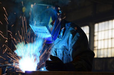 Fabrikada çalışan kaynakçılar metal üretiyorlar.