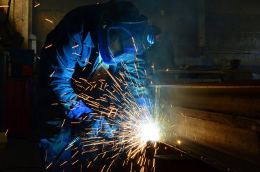 Fabrikada çalışan kaynakçılar metal üretiyorlar.