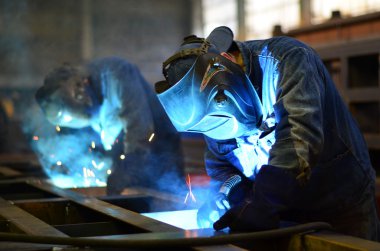 Fabrikada çalışan kaynakçılar metal üretiyorlar.