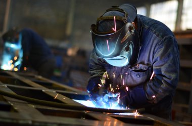 Fabrikada çalışan kaynakçılar metal üretiyorlar.