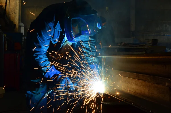 Fabrikada çalışan kaynakçılar metal üretiyorlar.