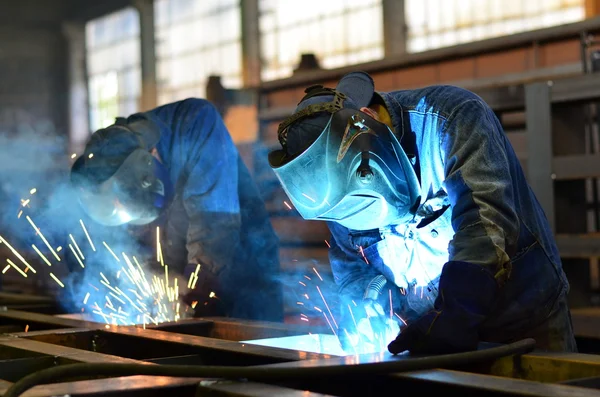 Fabrikada çalışan kaynakçılar metal üretiyorlar.