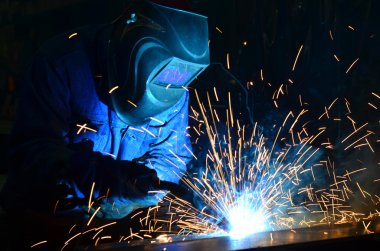 Fabrikada çalışan kaynakçılar metal üretiyorlar.