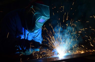 Fabrikada çalışan kaynakçılar metal üretiyorlar.