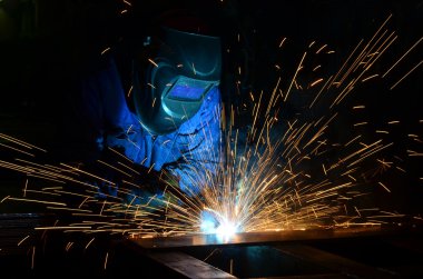 Fabrikada çalışan kaynakçılar metal üretiyorlar.