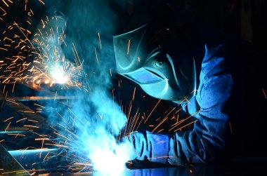 Fabrikada çalışan kaynakçılar metal üretiyorlar.