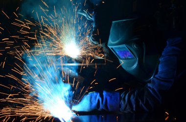 Fabrikada çalışan kaynakçılar metal üretiyorlar.