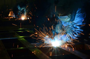 Fabrikada çalışan kaynakçılar metal üretiyorlar.